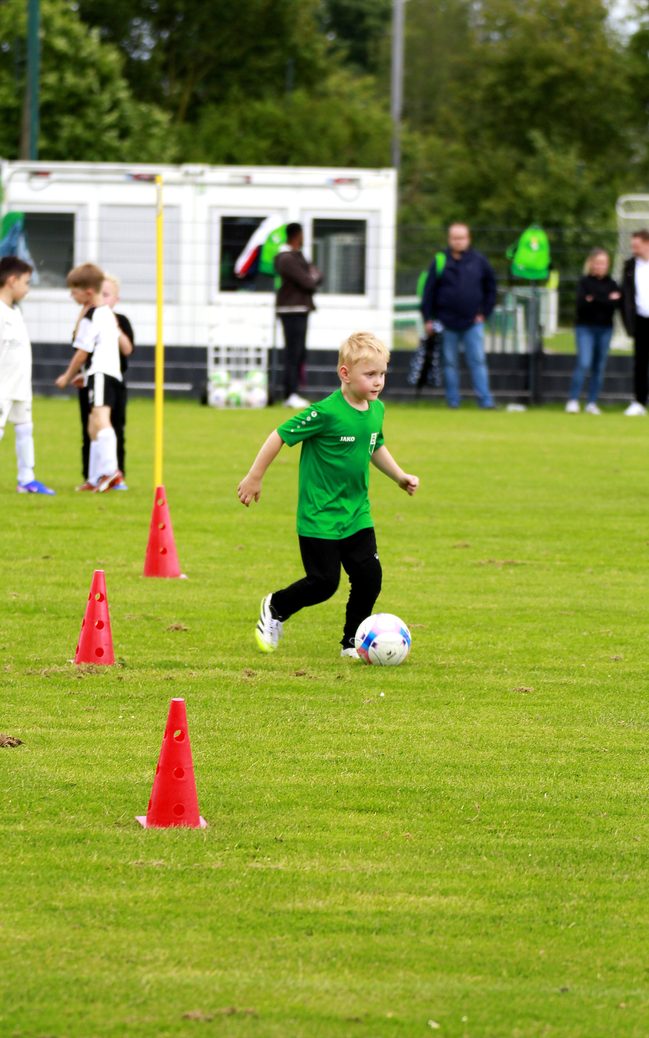 Kind in grünem Trikot mit Ball