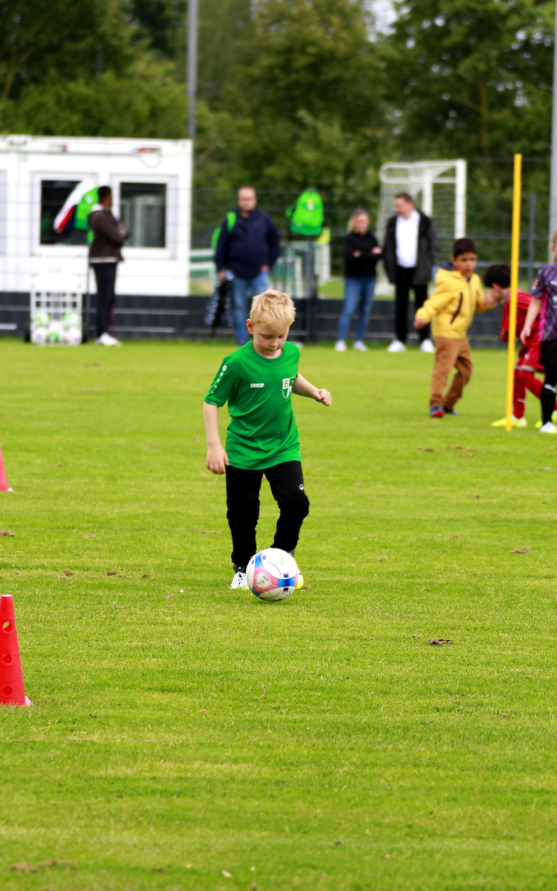 Kind in grünem Trikot führt den Ball