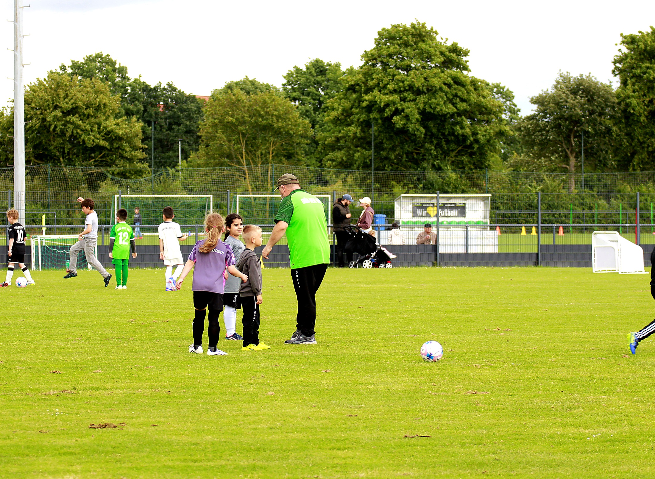 Trainer spricht mit Kindern auf dem Spielfeld