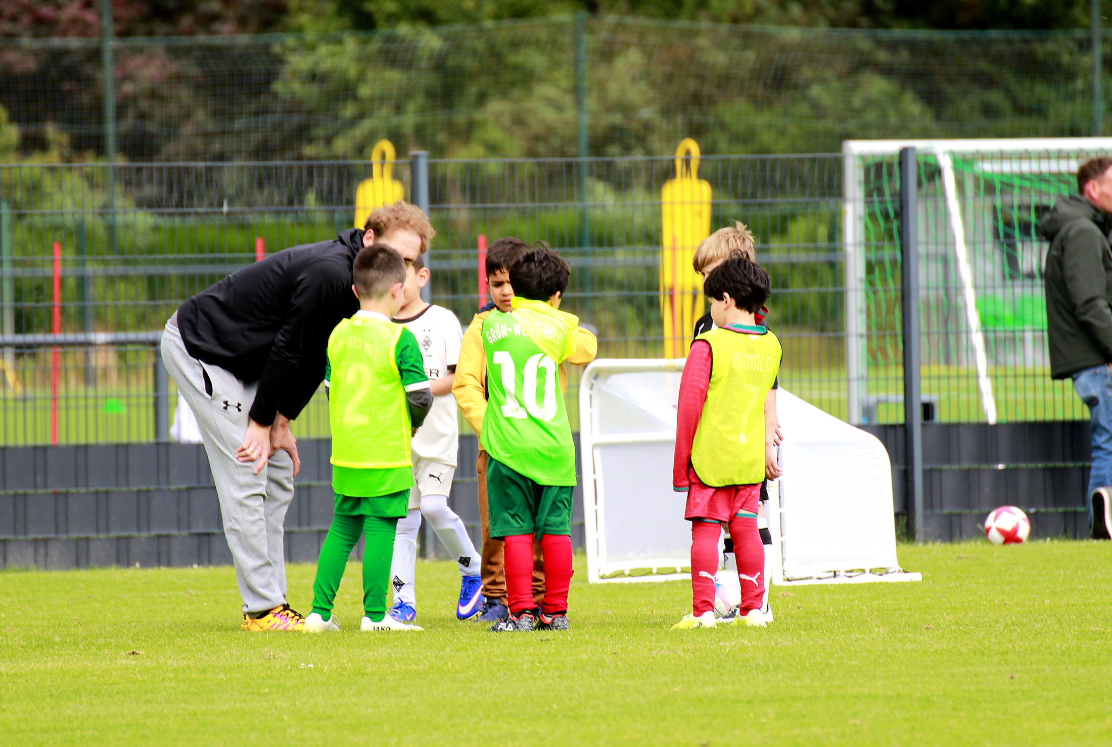 Trainer beugt sich zu Kindern im Teamkreis